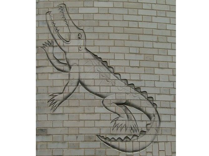 Od jednoho ruského kolegy dostal Rutherford přezdívku Krokodýl, což prý vyjadřovalo úctu k vědcově přímočarosti. Malůvka krokodýla na staré zdi Cavendishovy laboratoře měla Rutherforda připomínat. Foto: Wikimedia Commons Rutherfordovi přezdívali krokodýl.